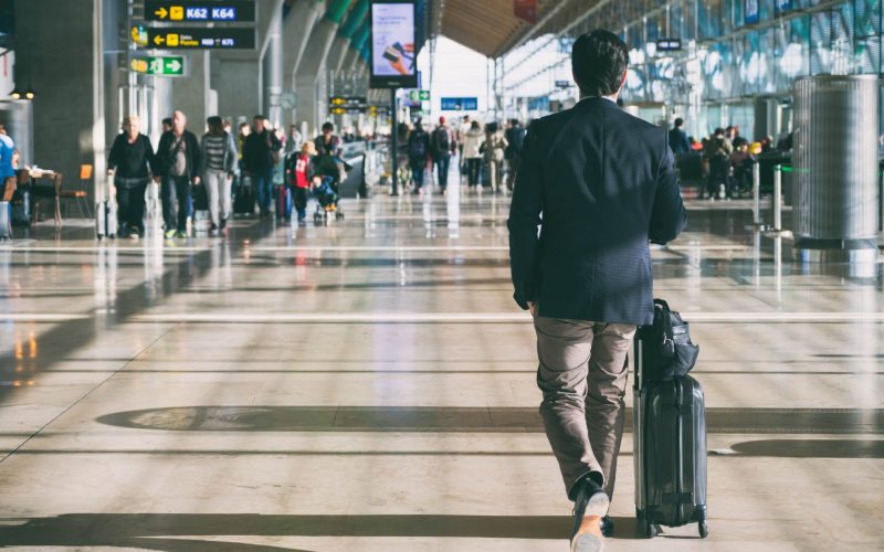 businessman-carrying-suitcase-while-walking-through-passenger-departure-terminal-min